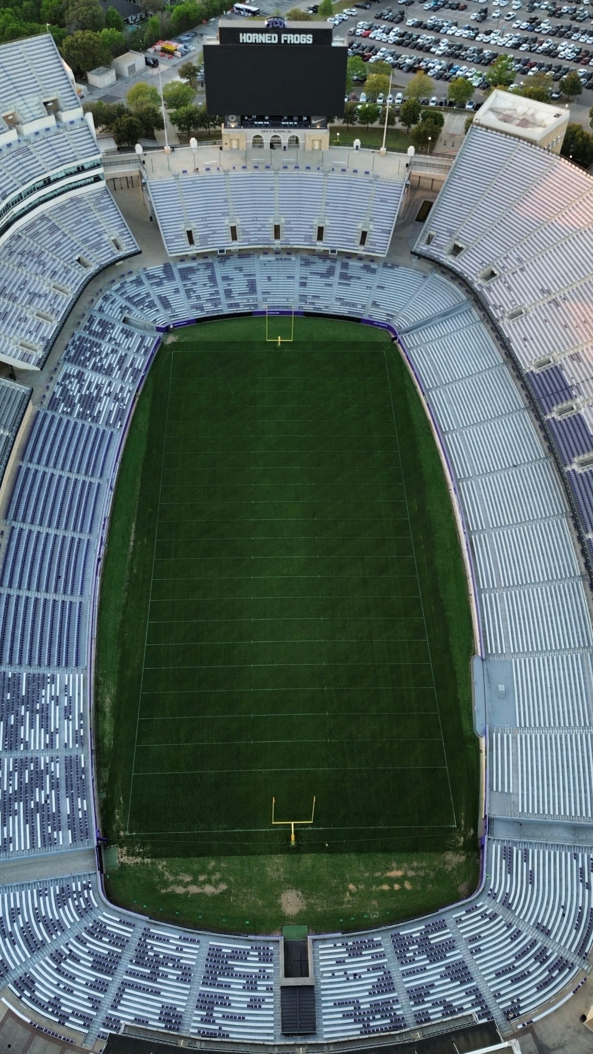 Aerial view of an empty football stadium with green turf and purple and grey seating.